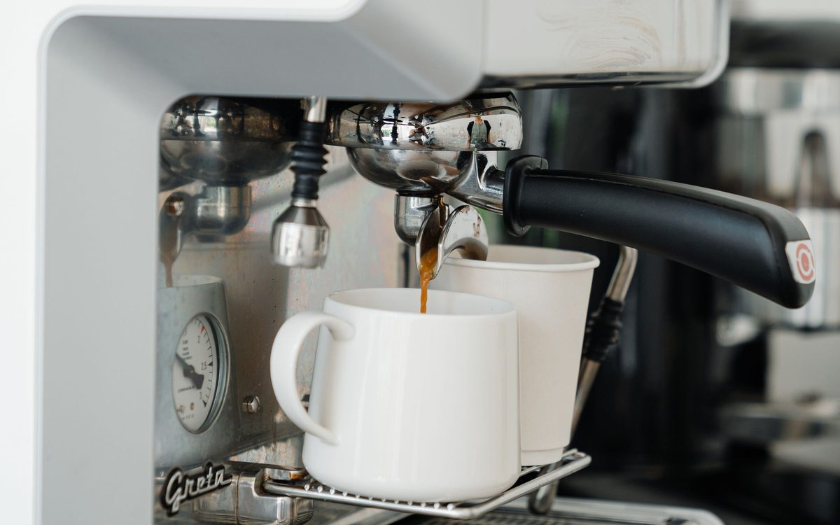Espresso läuft aus einer Siebträgermaschine in eine weiße Tasse