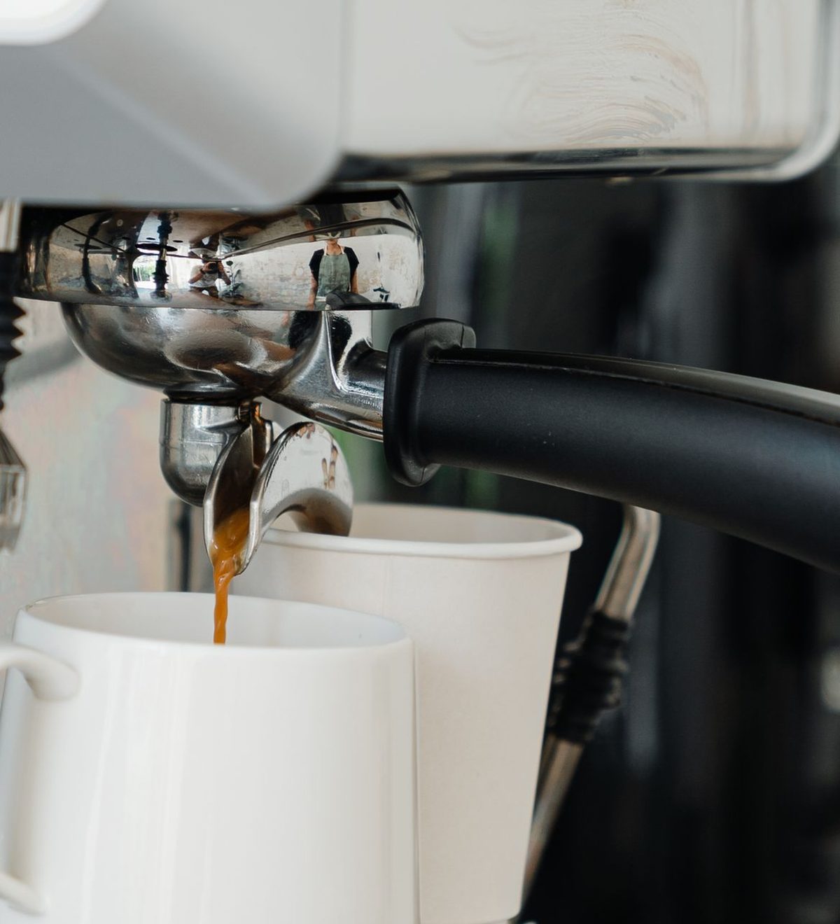 Espresso läuft aus einer Siebträgermaschine in eine weiße Tasse