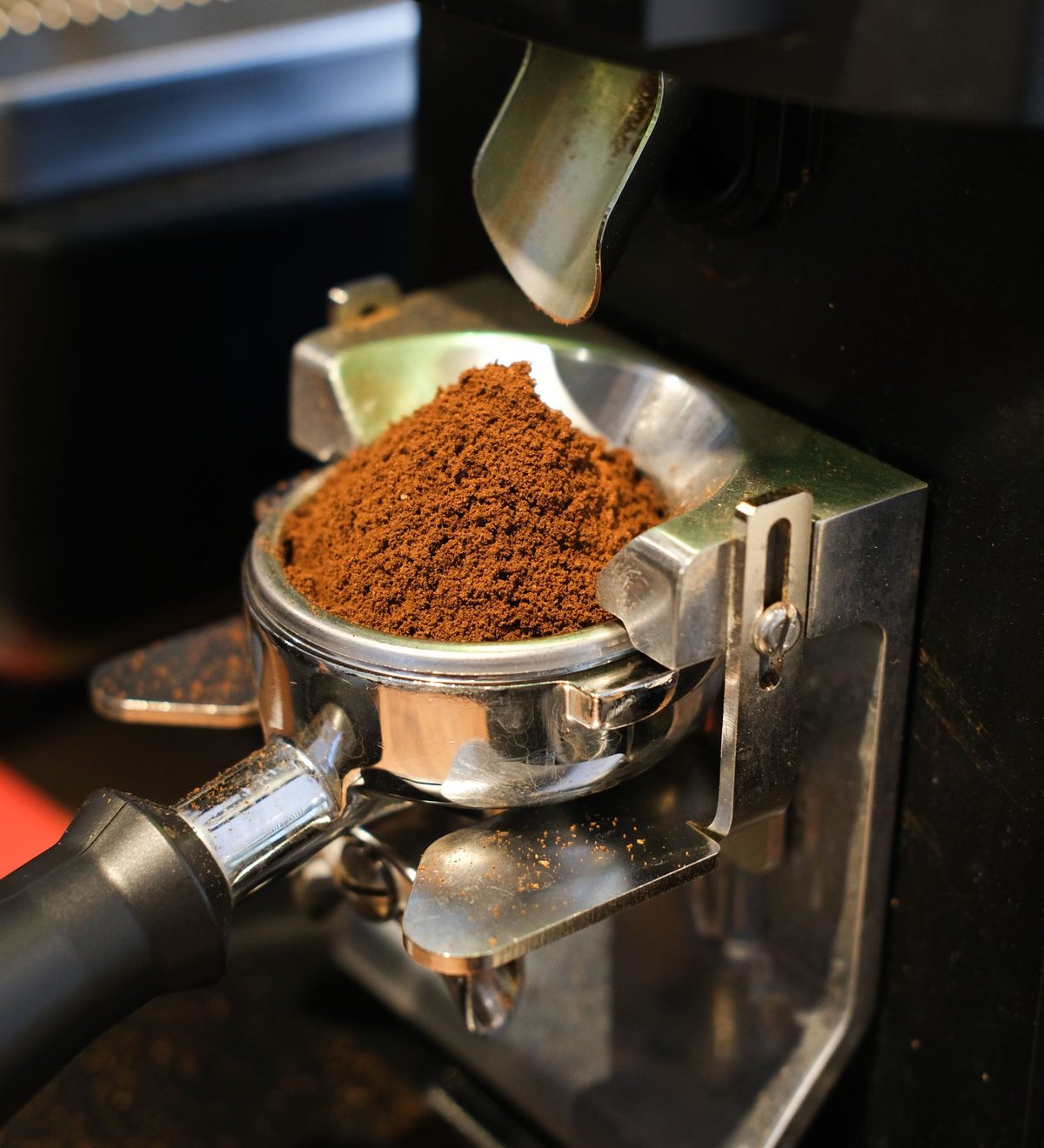 Frisch gemahlener Kaffee im Siebträger unter dem Auslauf einer Kaffeemühle