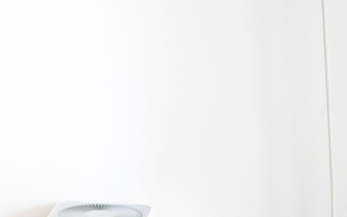 Weißer Luftreiniger neben einer Stehlampe in einem hellen, minimalistischen Raum