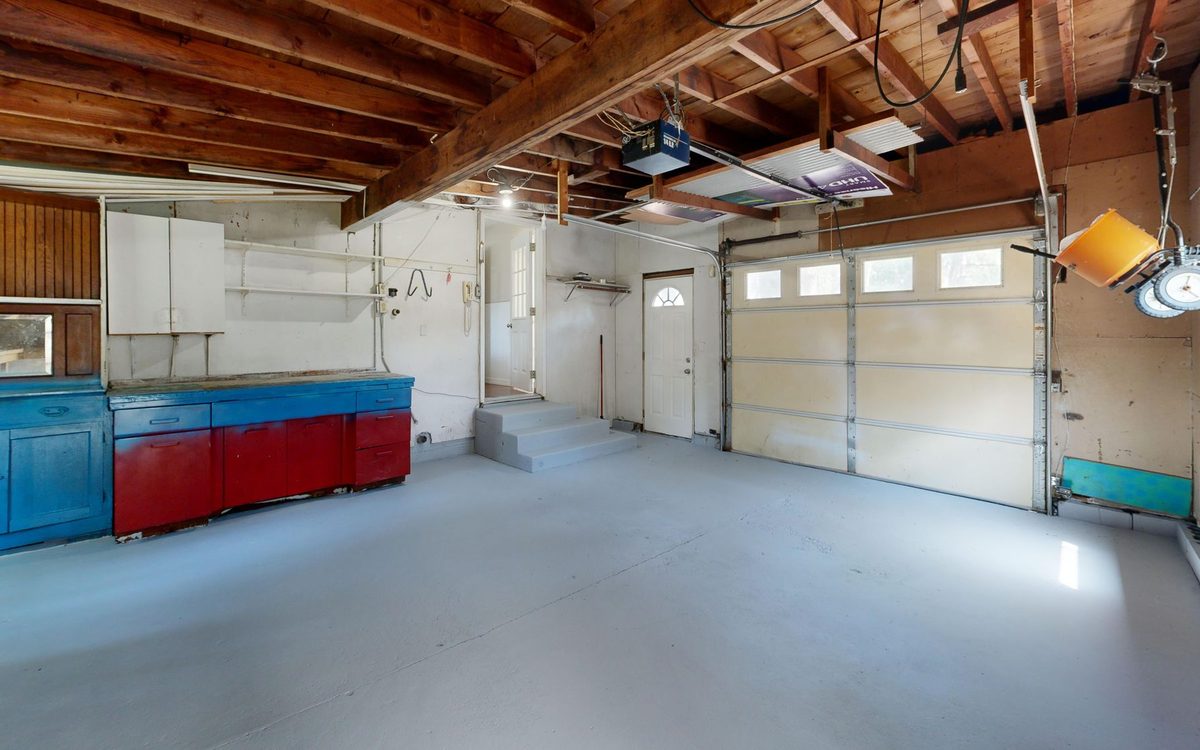 Aufgeräumte, helle Garage mit Holzbalkendecke und Werkbank