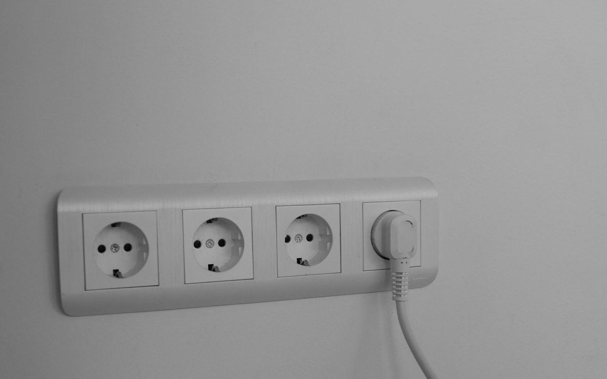 Mehrfach-Wandsteckdose mit eingestecktem weißem Stecker an einer hellen Wand