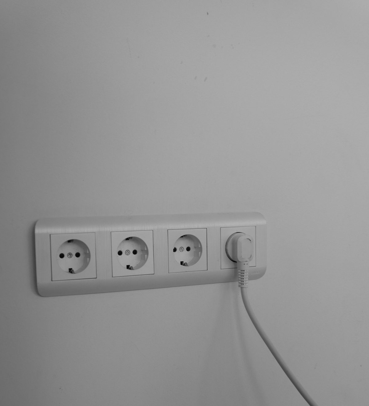 Mehrfach-Wandsteckdose mit eingestecktem weißem Stecker an einer hellen Wand