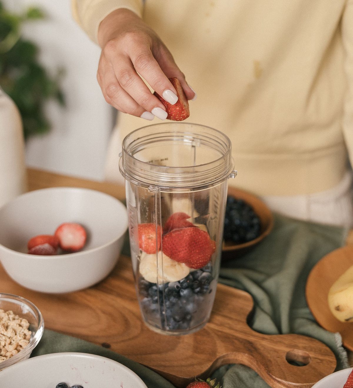 Erdbeeren, Blaubeeren und Banane werden für einen Smoothie in einen Mixbecher gegeben
