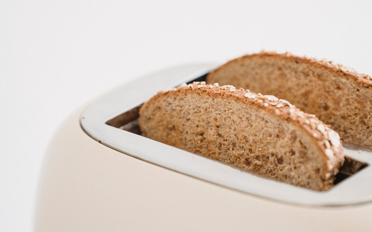 Zwei Vollkornscheiben stecken in einem cremefarbenen Toaster