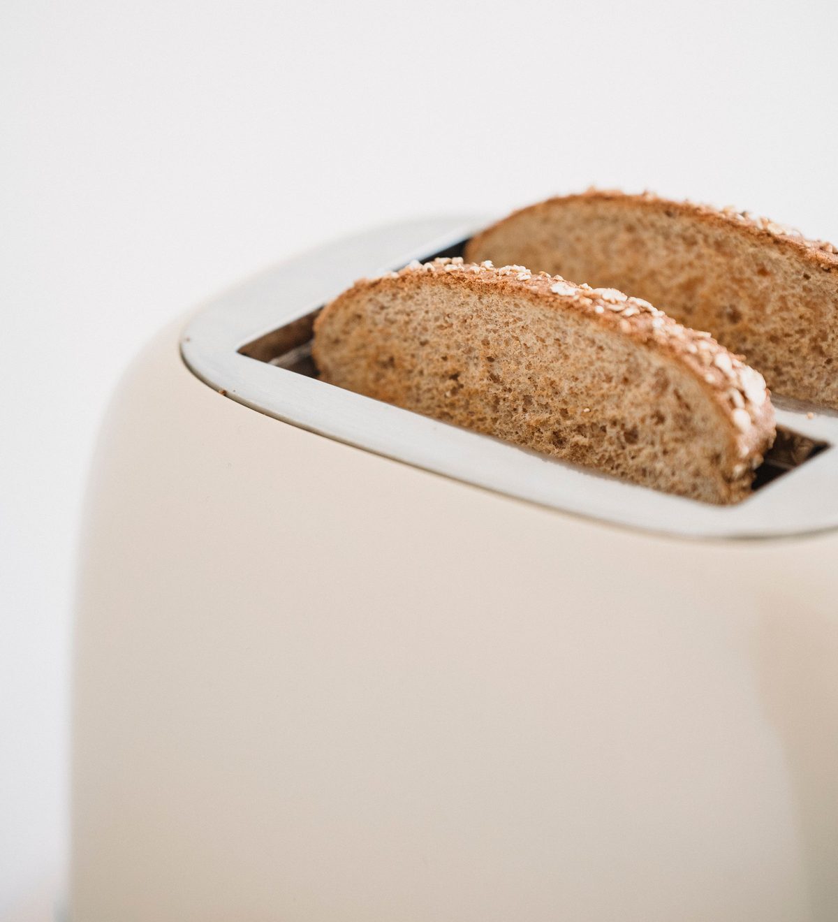Zwei Vollkornscheiben stecken in einem cremefarbenen Toaster