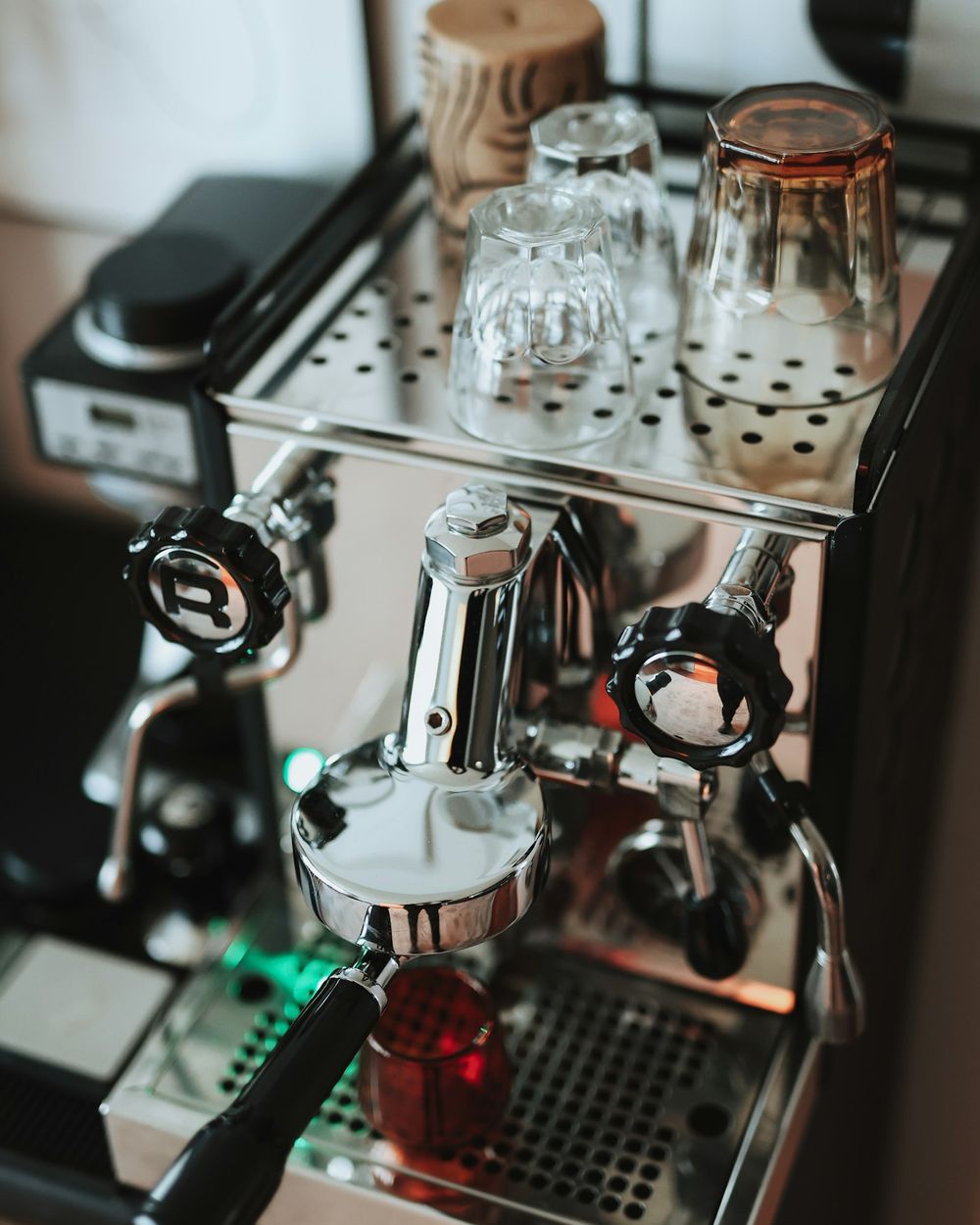 Espressomaschine aus Edelstahl mit Gläsern und Tassen auf der Arbeitsplatte